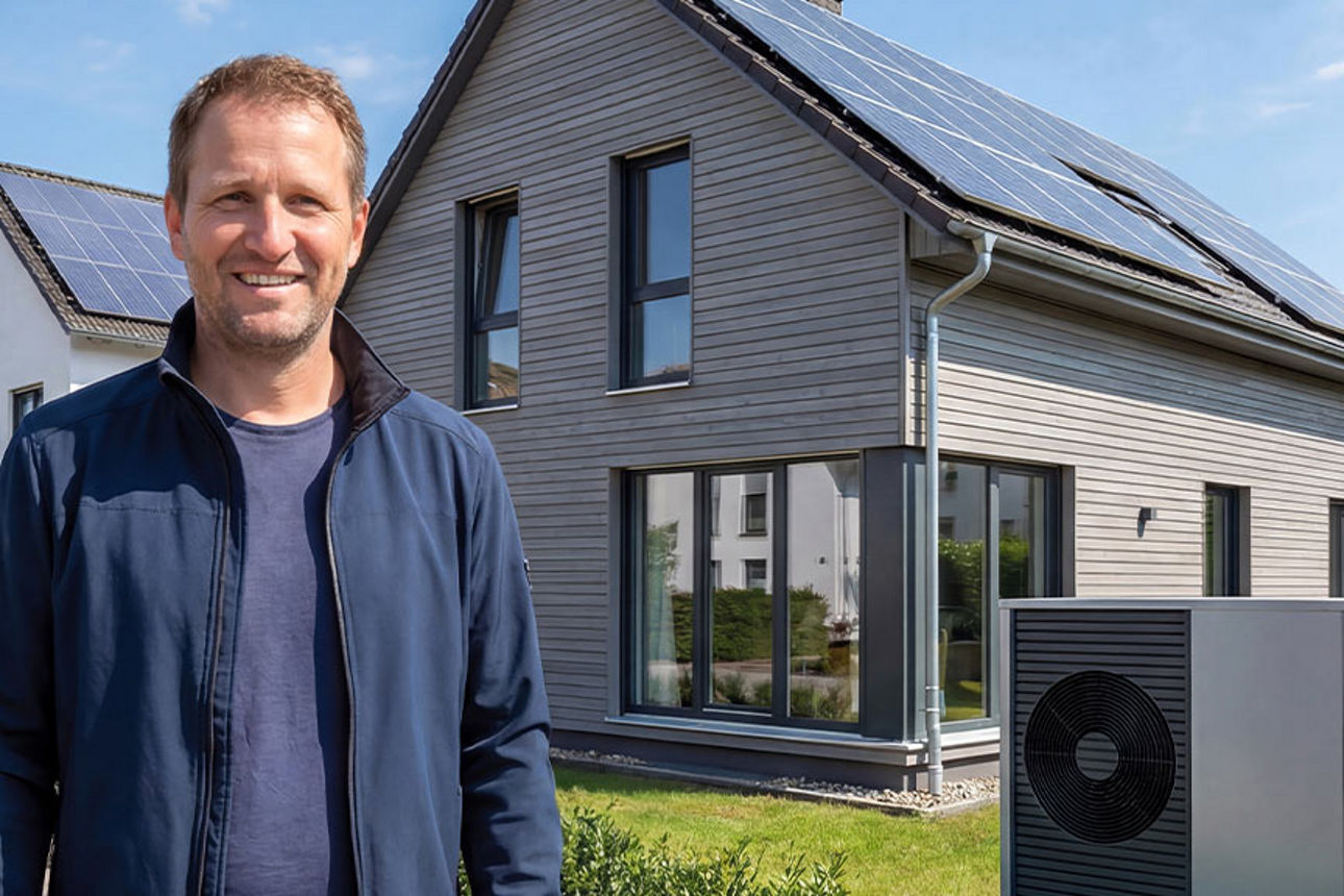 Ein Mann mit glücklicher Mimik steht vor einem modernisierten Haus.