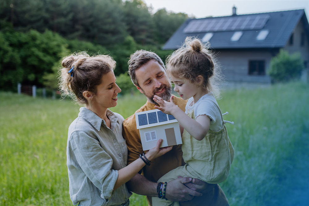 Junge Familie vor ihrem Haus mit Photovoltaikanlage
