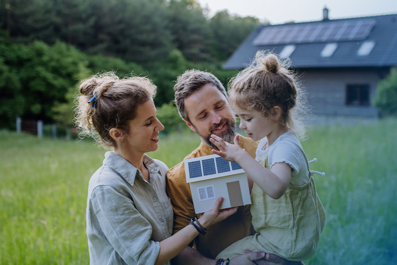 Jung Familie vor ihrem neuen Haus mit Photovoltaikanlage