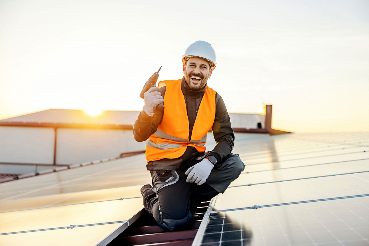 Ein Arbeiter bereitet die Installation von Solarmodulen vor und lächelt in die Kamera.