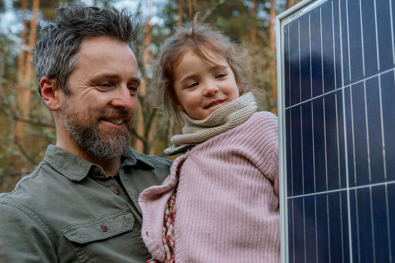 Vater und Kind stehen neben einem Solarpanel