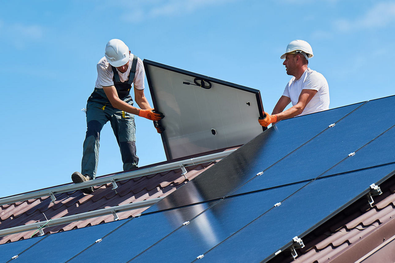 Zwei Handwerker montieren Solarzellen auf einem Hausdach
