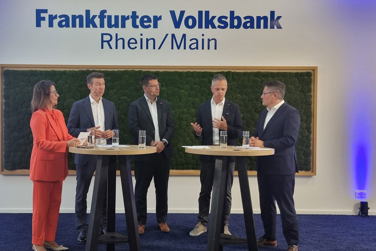 Eine Frau und drei Männer im Austausch vor einer Mooswand