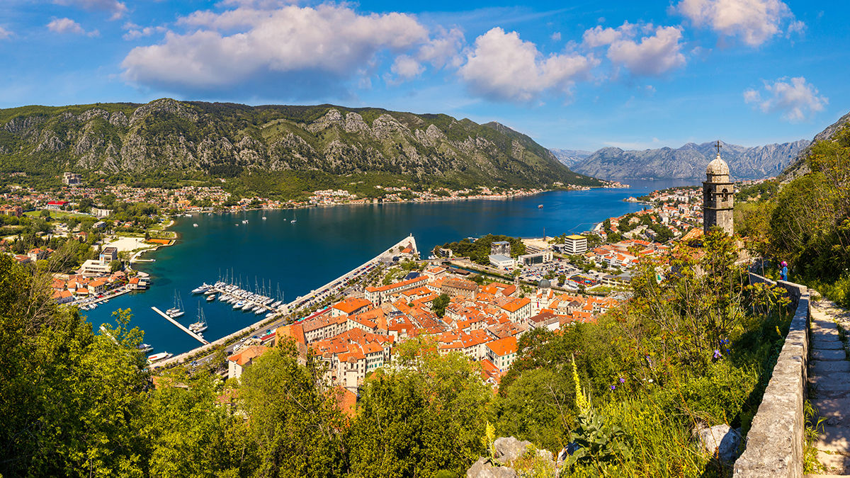 Bucht zwischen Gebirgszügen an einem engen Meeresarm, umgeben von alten Gebäuden