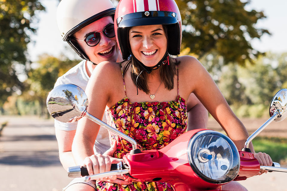 Zwei lachende junge Menschen auf einem Moped