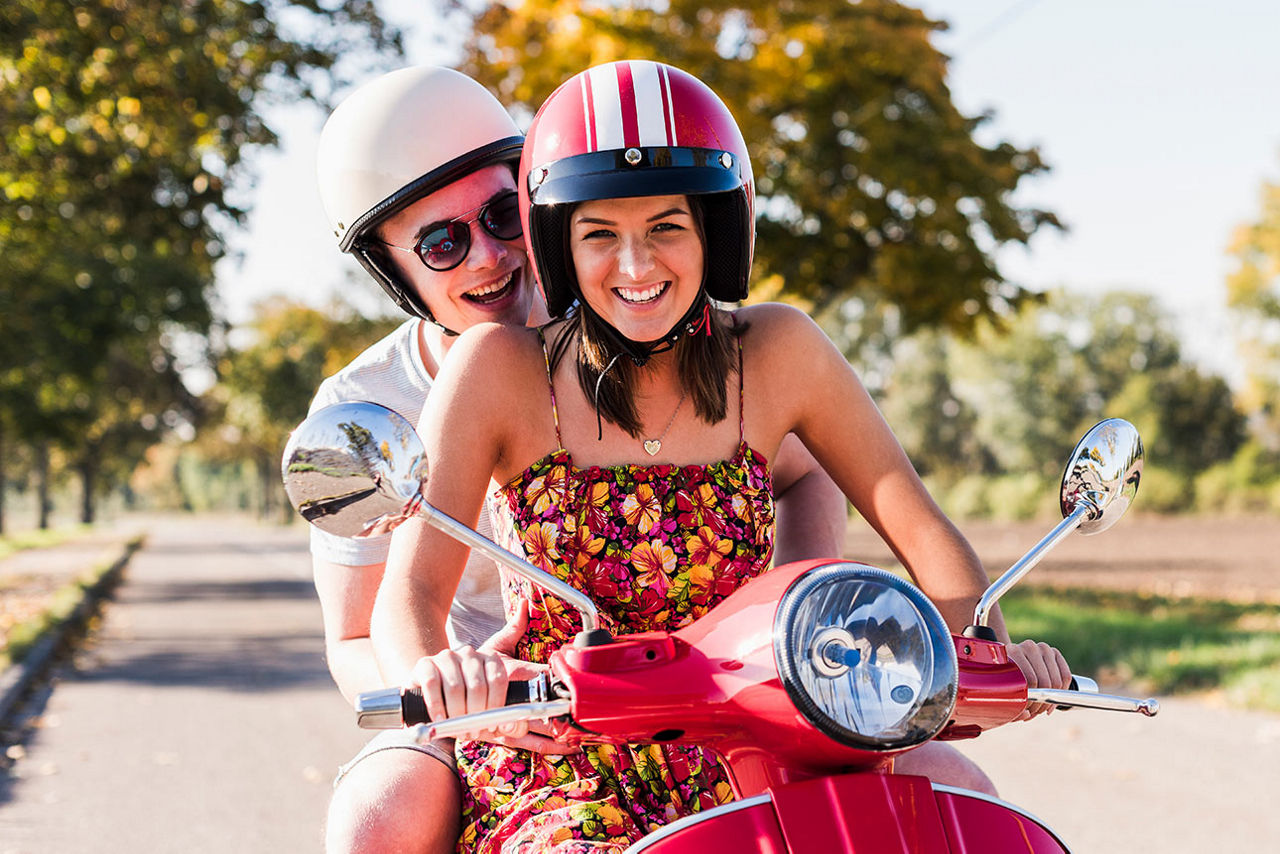 Zwei Freunde fahren gemeinsam auf einem Roller.