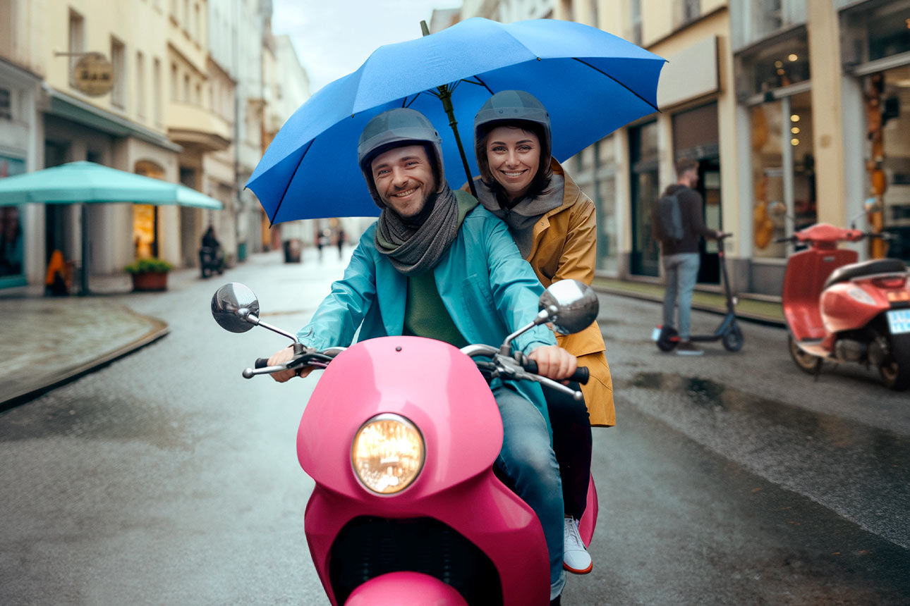 Mann und Frau unter einem blauen Schirm auf einem Moped