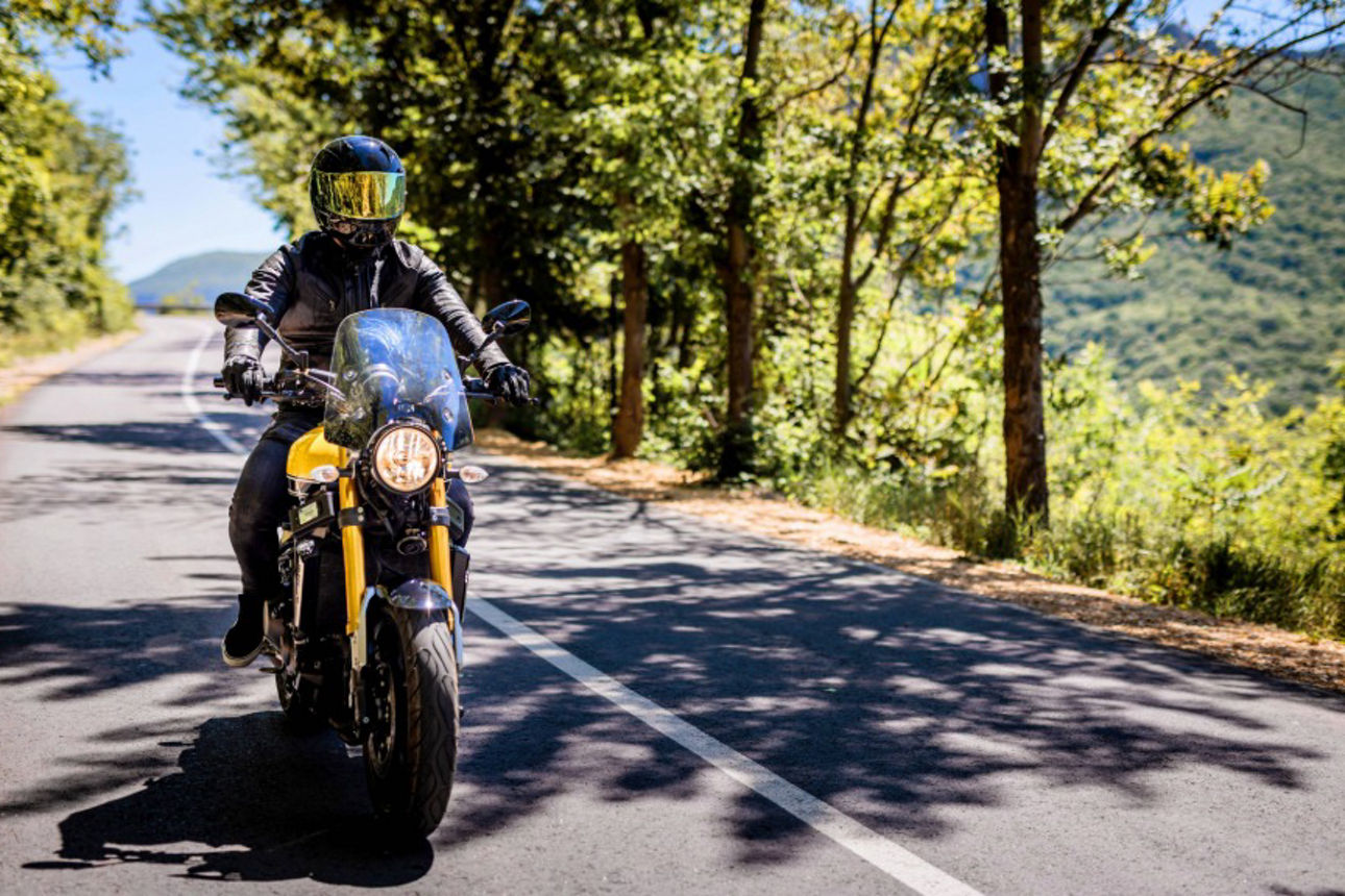 Biker mit voller Sicherheitsausrüstung genießt die Fahrt auf der Landstraße