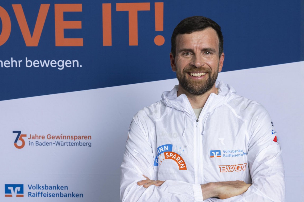 Person vor MOVE IT!-Banner und Gewinnspar-Logos zum 75-jährigen Jubiläum.