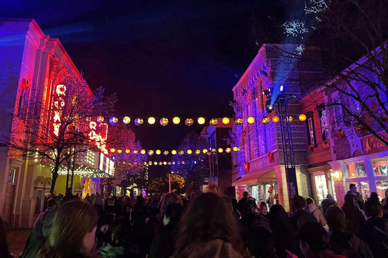 Häuser im Movie Park bei Dunkelheit welche mt farbigen Licht in Sezene gesetzt werden. Auf der Straße laufen Menschen.