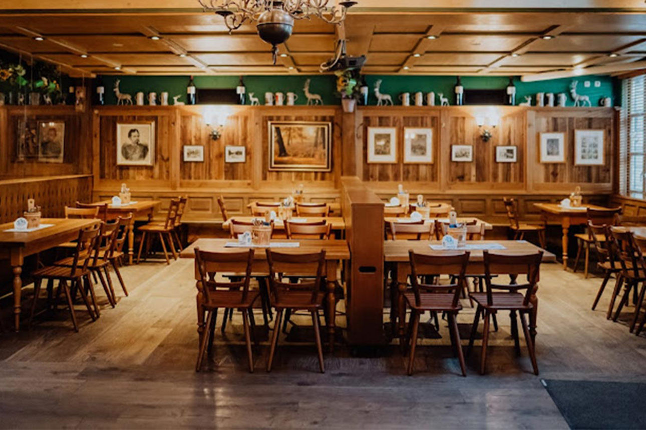Ein holzvertäfelter Gastraum mit Stühlen und Tischen