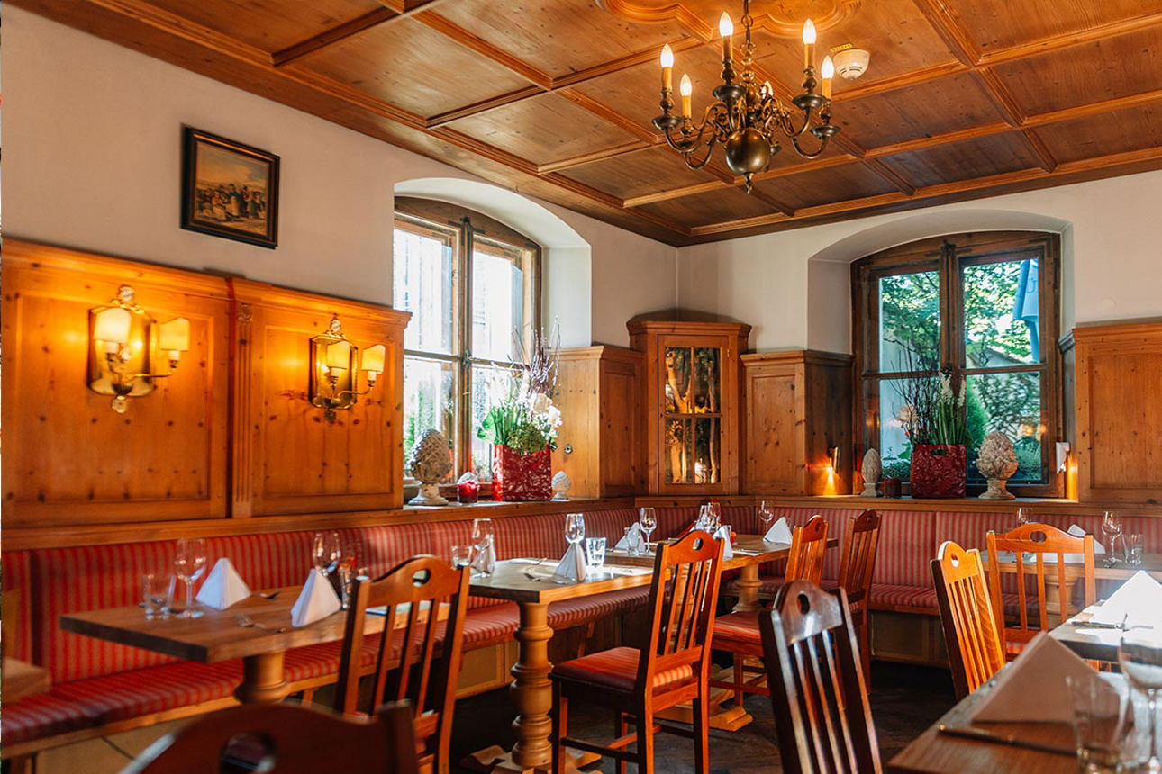 Ein holzvertäfelter Gastraum mit Stühlen und Tischen
