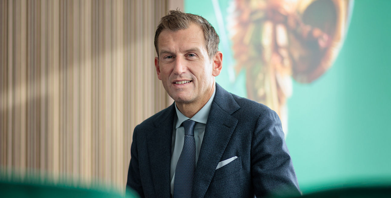 Unser Vorstand Michael Dandorfer sitzt vor einer Holzwand und einem grünem Gemälde