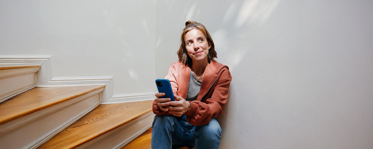 Eine junge Frau mit Handy sitzt auf einer Treppe