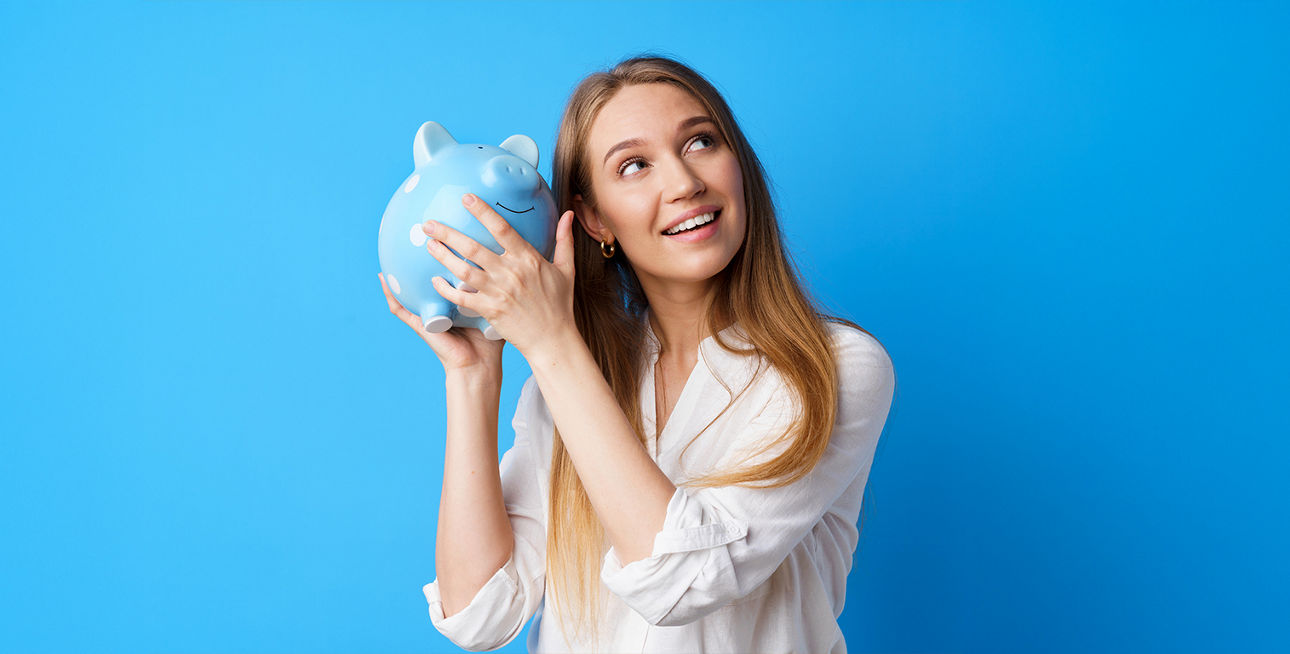 Eine junge Frau mit einem Sparschwein auf blauem Hintergrund