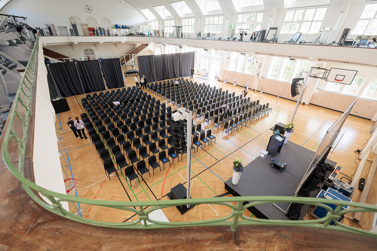 Eine Jugendstil-Sporthalle mit vielen leeren Stühlen