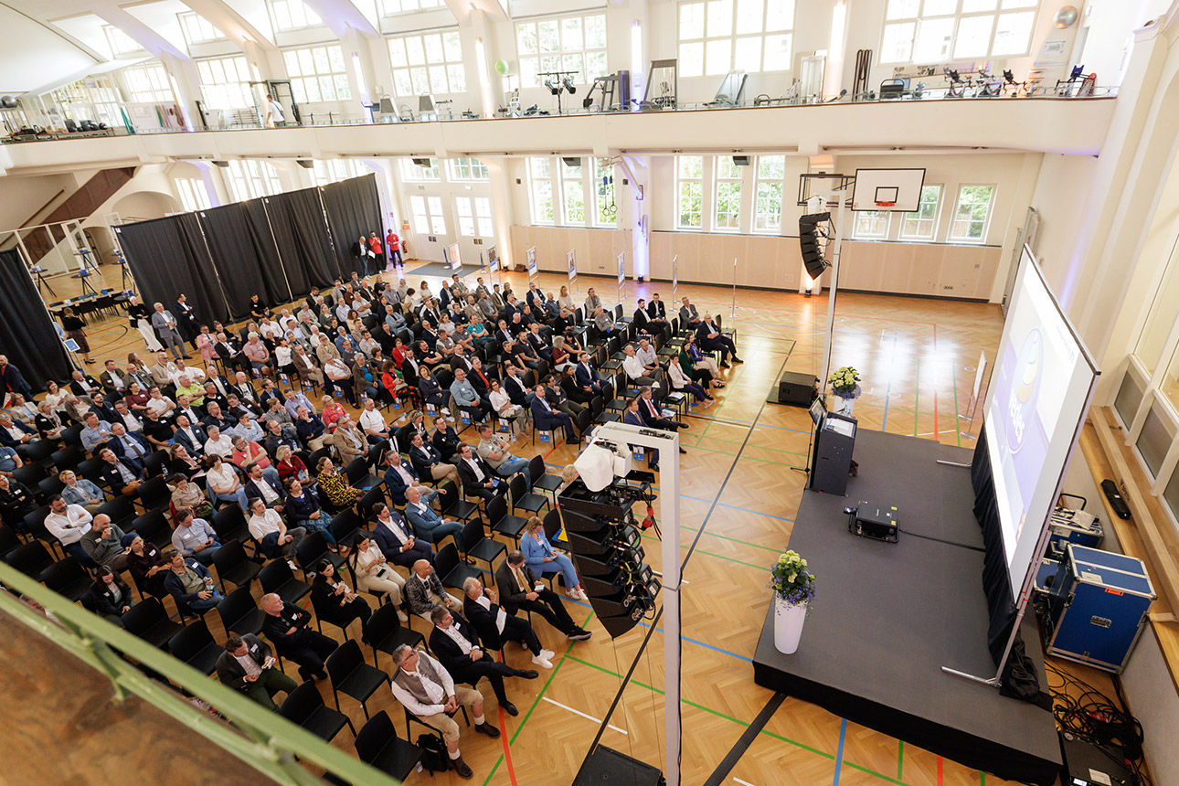 Zwei lächelnde Personen vor einem Podium