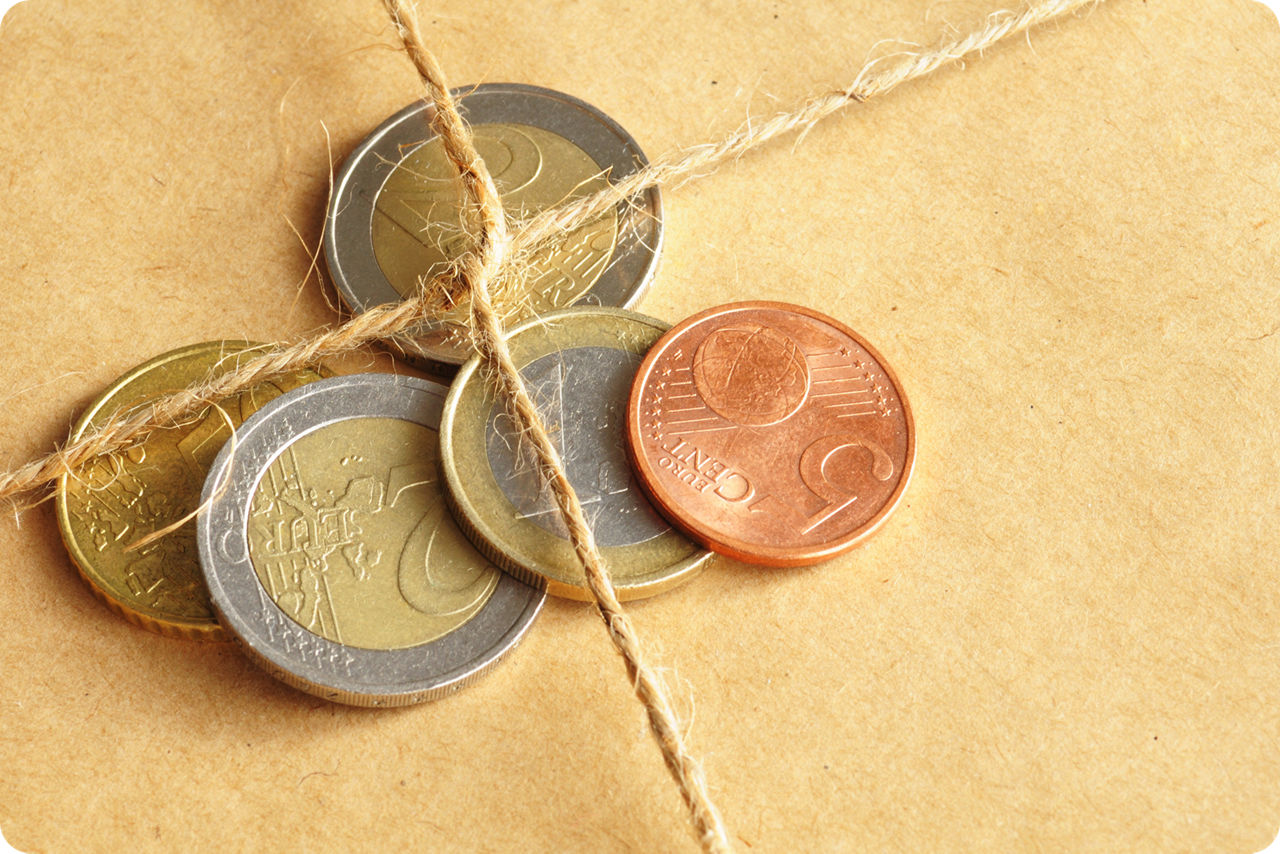 Verschiedene Euro-Münzen sind von einer Paketschnur eingebunden