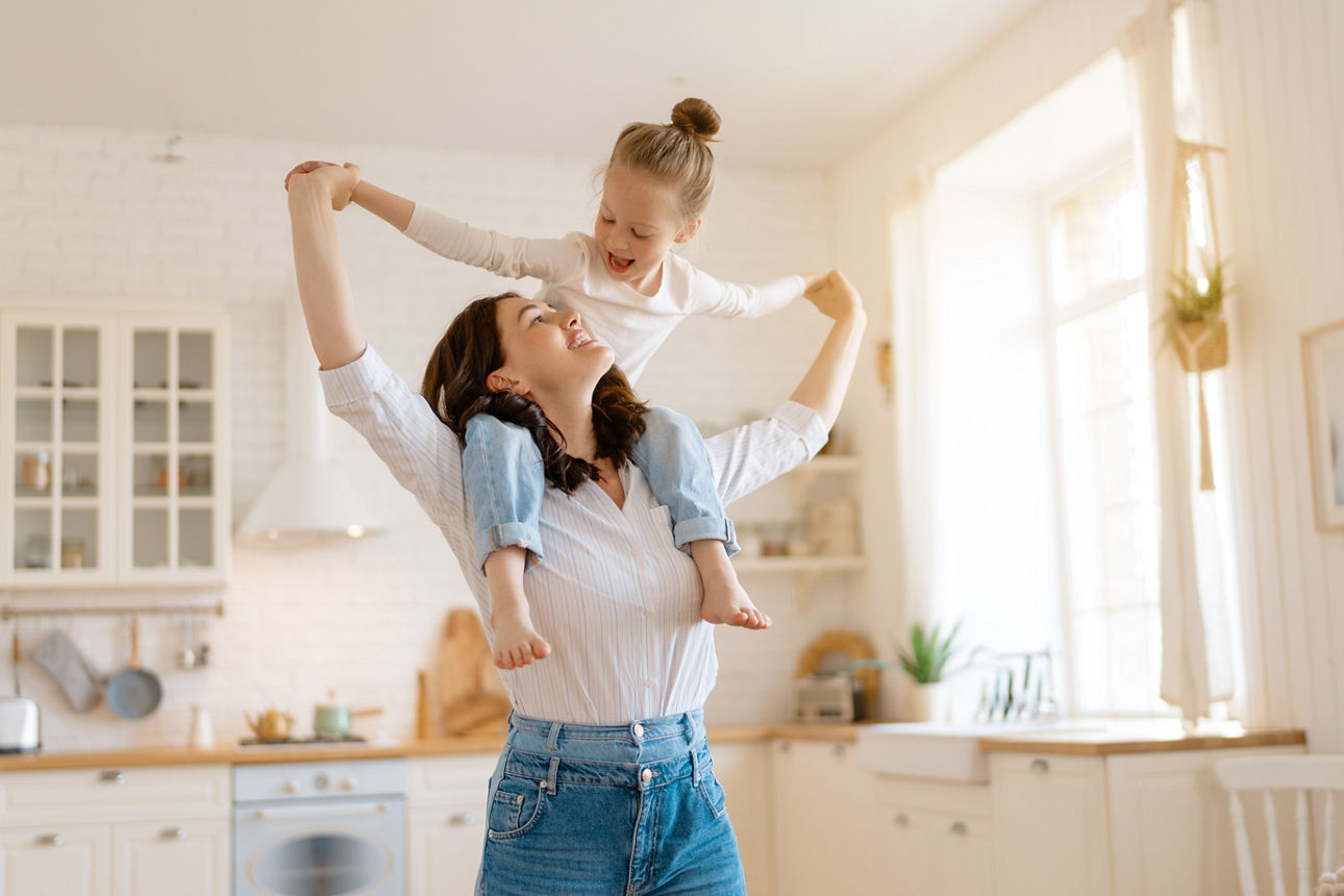 Mutter trägt Tochter auf den Schultern in der Küche