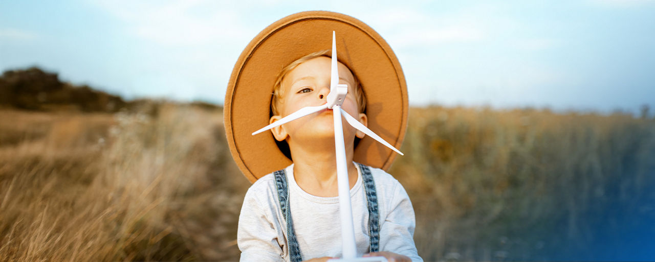 Kleiner Junge mit Strohhut und Modell eines Windkraftwerks