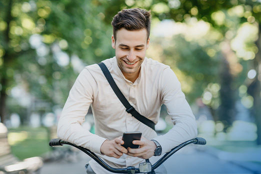Junger Mann auf Fahrrad mit dem Smartphone