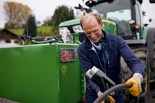 Ein Landwirt mit seinem Traktor vor einer E-Ladesäule