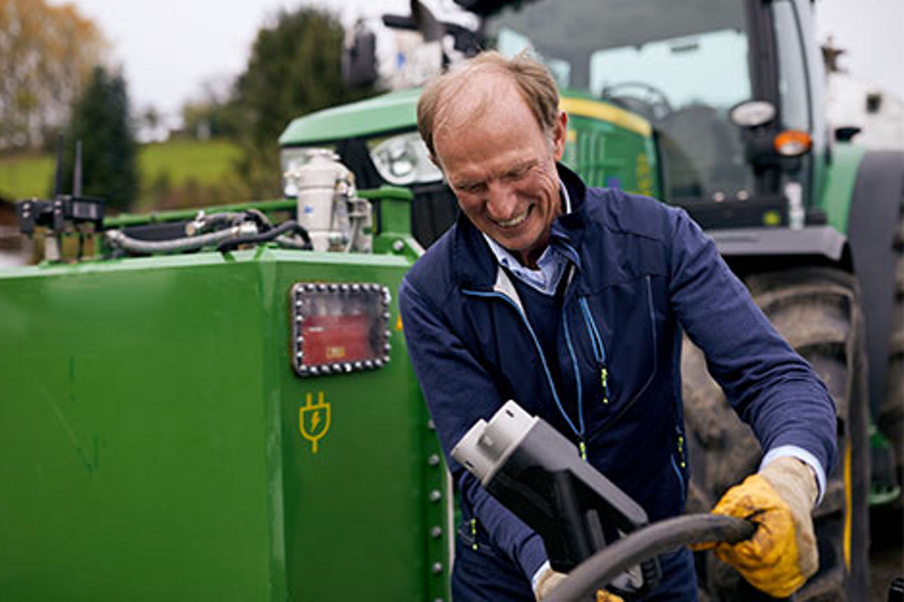 Ein Landwirt mit seinem Traktor vor einer E-Ladesäule