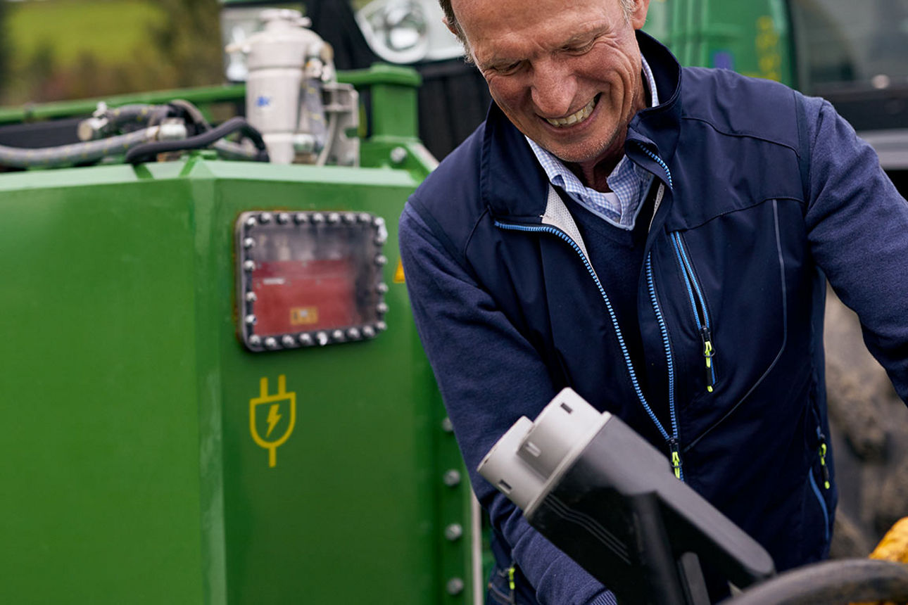 Zwei Hände, die ein Herz formen, vor einer grünen Landschaft 