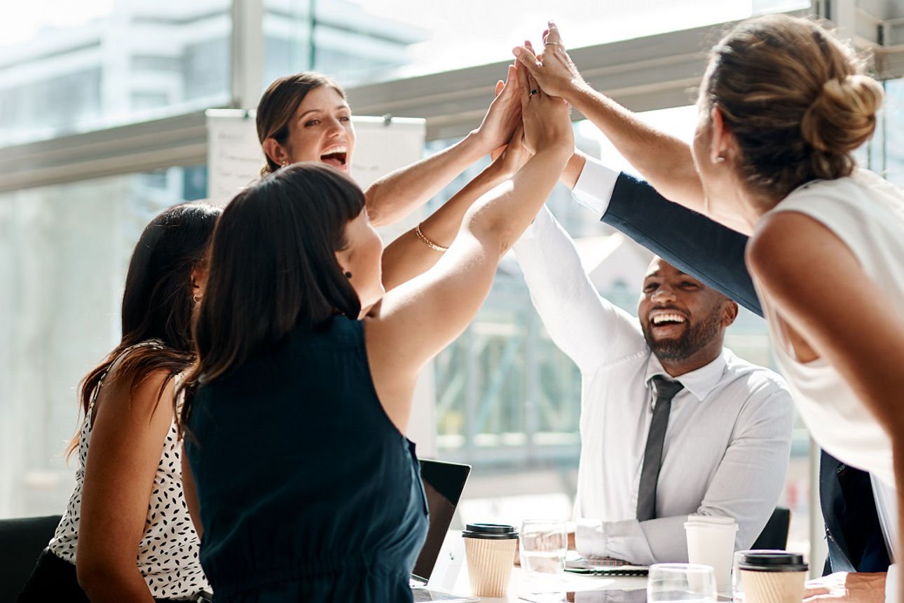 Team klatscht über der Mitte des Tisches die Hände zusammen