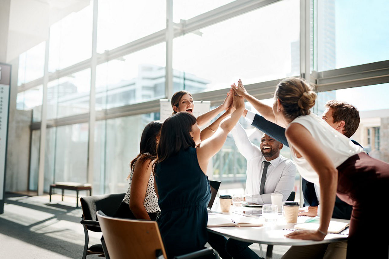 Team klatscht über der Mitte des Tisches die Hände zusammen