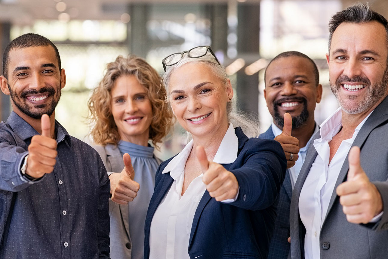 Lächelnde Kollegen die alle den Daumen hoch halten