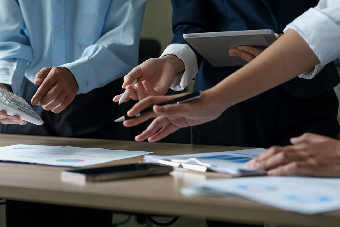 Nahaufnahme von mehreren Händen beim Arbeiten auf einem Schreibtisch