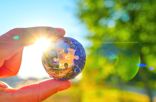 Kleine Puzzelweltkugel wird in einer Hand gegen das Licht gehalten