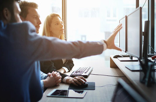 Drei Kollegen schauen auf einen Monitor