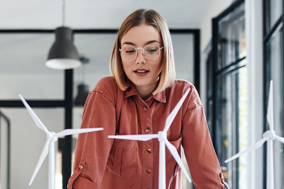 Eine Frau guckt auf Modelle von Windkrafträdern