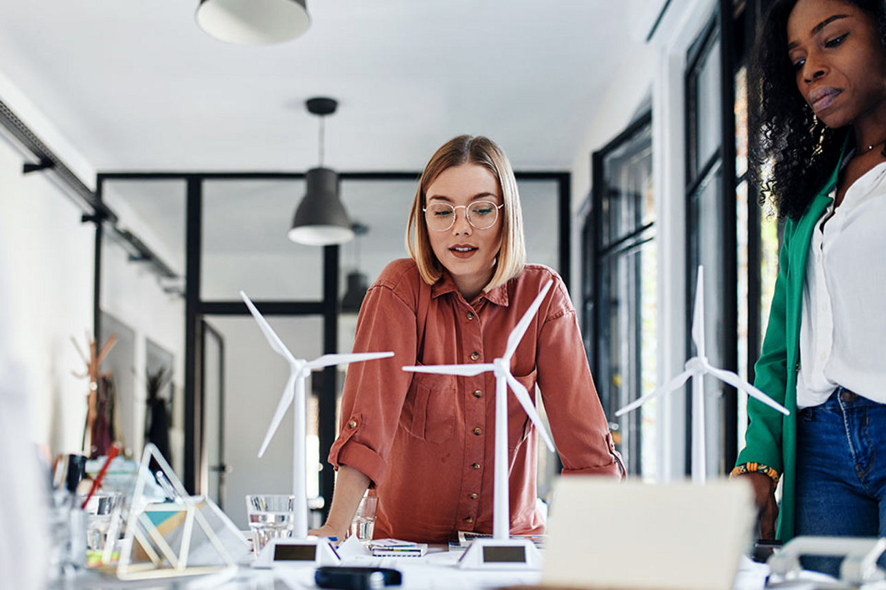 Zwei Frauen stehen vor Modell-Windrädern