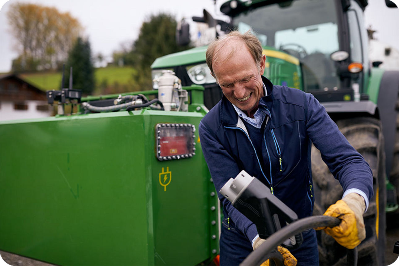 Ein Landwirt mit seinem Traktor vor einer E-Ladesäule