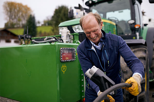 Ein Mann in Arbeitskleidung steht vor einem Traktor