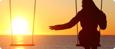 Eine Frau sitze allein auf einer Schaukel vor dem Sonnenuntergang