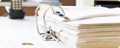 Ein geöffneter Ordner mit Unterlagen liegt auf einem Schreibtisch