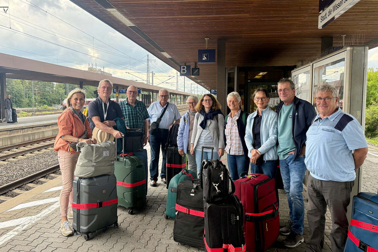 Reisegruppe mit Koffern auf dem Bahnsteig.