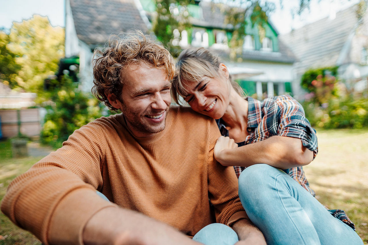 Pärchen sitzt im Garten - im Hintergrund ist ein Haus
