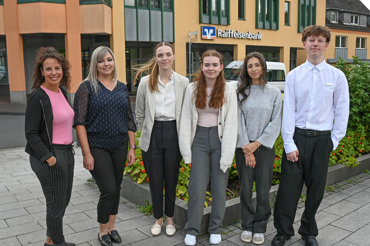 Ausbildungsleiterin Sabrina Nickel-Di Stasio steht mit vier neuen Kolleginnen und einem neuen Kollegen vor der Hauptstelle in Neustadt