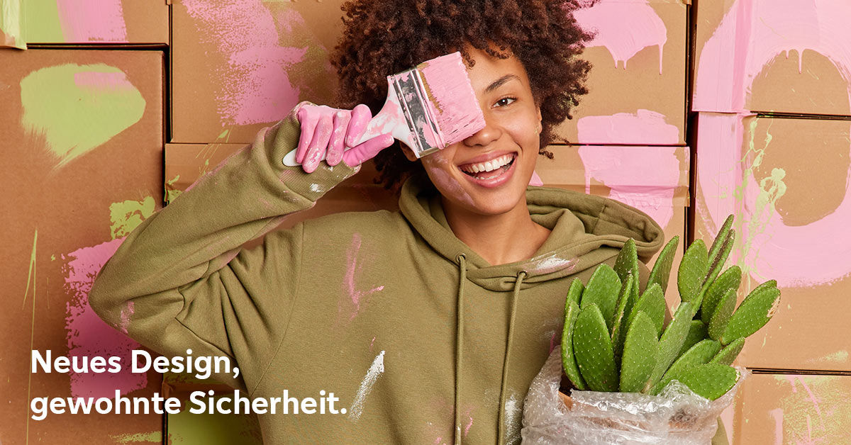 Eine junge Frau steht mit Farbflecken auf der Kleidung und einem Pinsel zwischen Mund und Nase geklemmt in einem Atelier