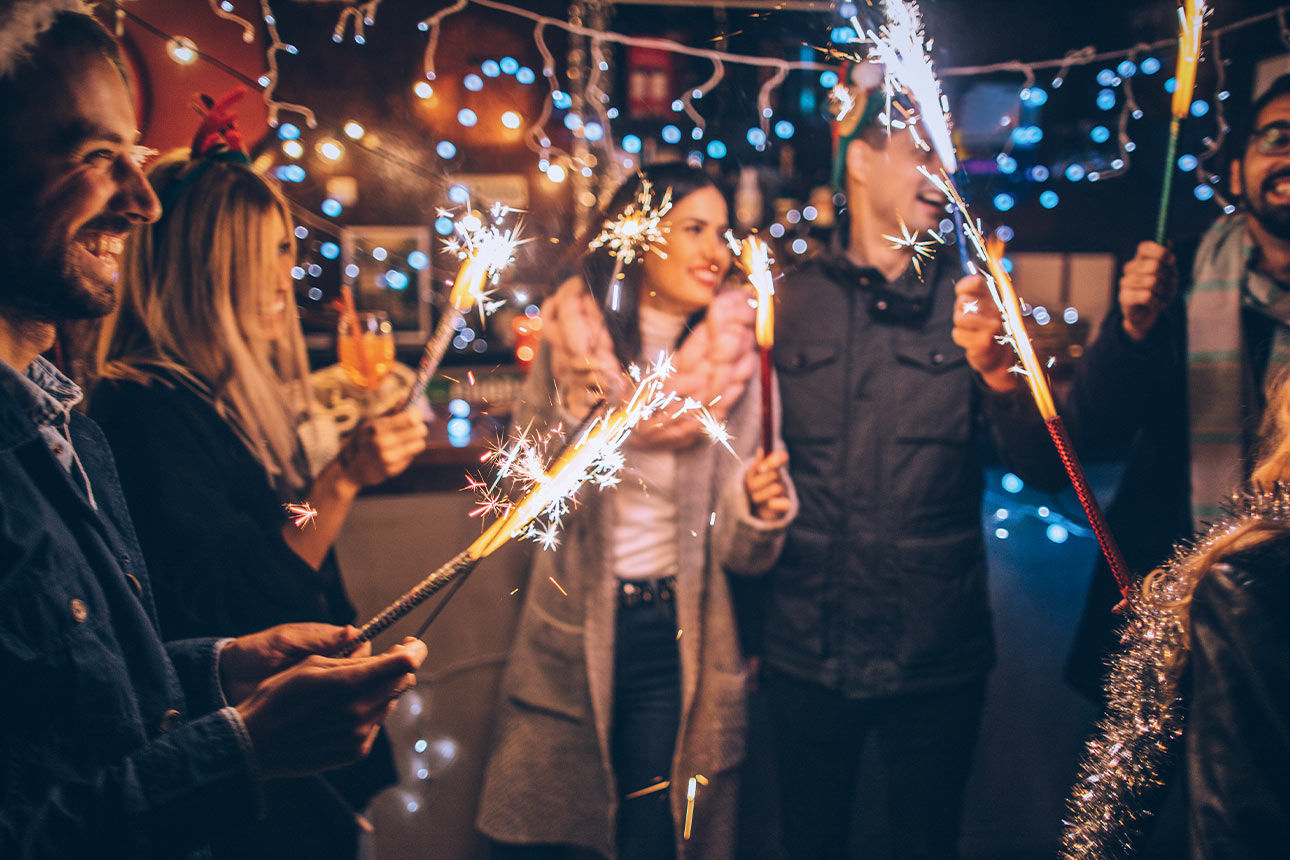 Eine Gruppe von Menschen feiert gemeinsam Silvester mit Wunderkerzen und guter Stimmung.