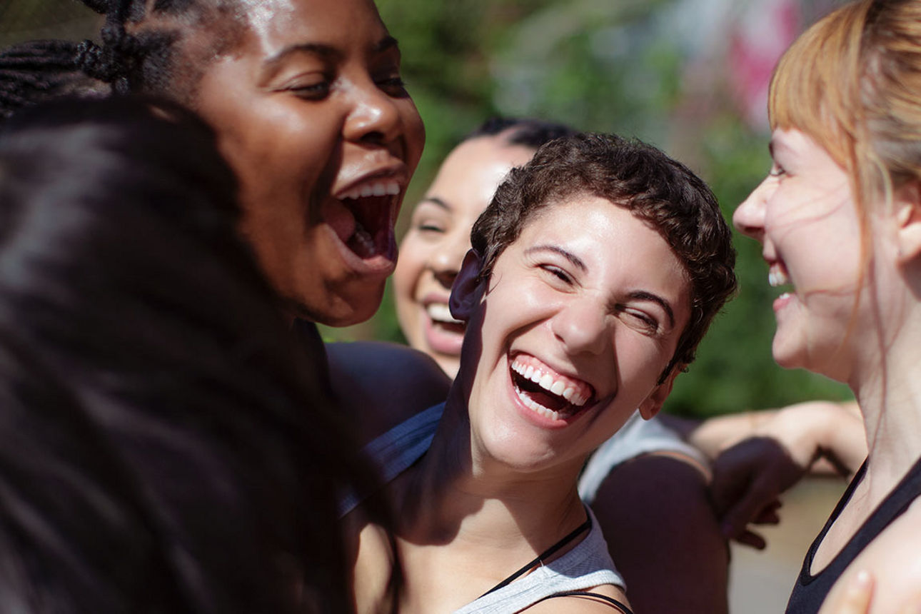 Junge Frauen stehen lachend in einer Gruppe zusammen.