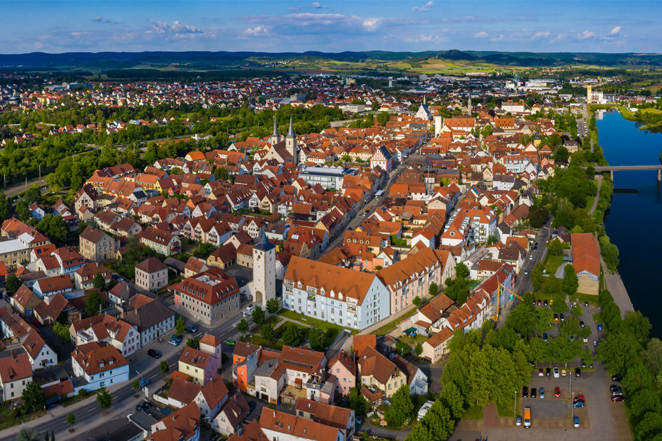 Luftaufnahme der Stadt Haßfurt mit Main und den Haßbergen im Hintergrund