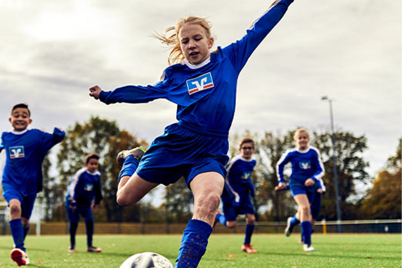 Eine Kinder-Fußballmannschaft in Volksbank-Trikots beim Spiel 