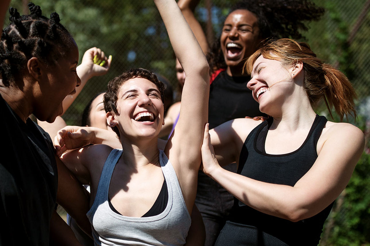 Junge Frauen jubeln mit hochgestreckten Armen.