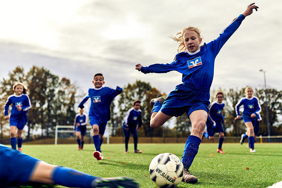 Eine Kinder-Fußballmannschaft in Volksbank-Trikots beim Spiel 